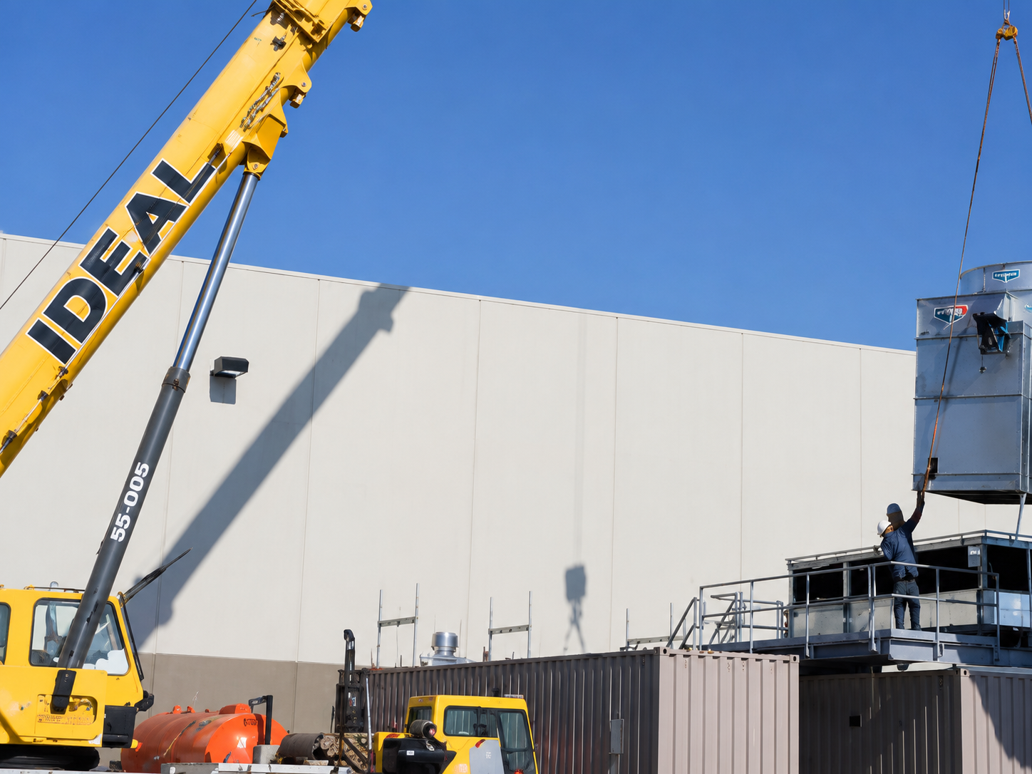 Crane lifting HVAC equipment at a commercial site